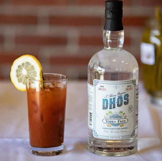  Bloody Mary with lemon wedge and bottle of Dos Vinas vodka on a table.